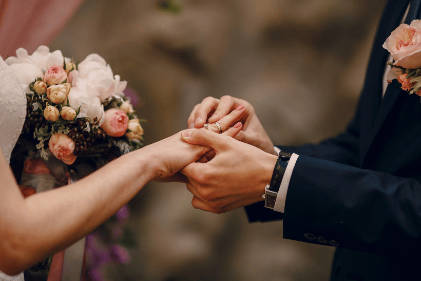 groom putting a ring on bride's finger